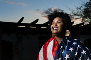 This is a stock image of a women with the USA flag wrapped around her.