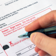 Closeup voter signing ballot envelope